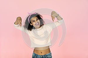 Happy young african girl blogger point fingers down isolated on pink background