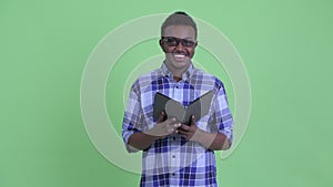Happy young African hipster man reading book and waving hand