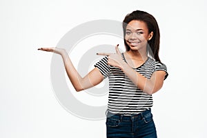 Happy young african lady holding copyspace in hand while pointing