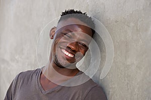 Happy young african man leaning against wall