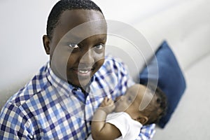happy young African man playing with his little baby while lying in bed
