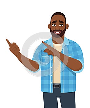 Happy young African man presenting or pointing finger to copy space. Trendy black person showing hand to introduce something.