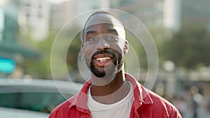 Happy young African man standing on city street outdoors looking at camera.