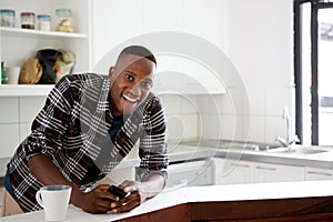 Happy young african man standing in the kitchen