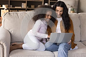 Happy young African mother and daughter girl watching movie