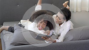 Happy young African mother using tablet computer with daughter for education and learning on bed in the bedroom