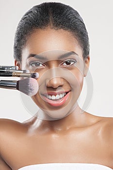 Happy young african woman with cosmetic tools