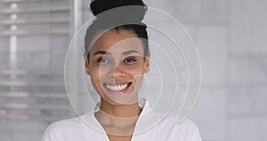 Happy young african woman looking at camera in bathroom