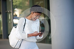 Happy young african woman reading text on cell phone