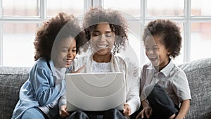 Happy young african woman watching movie on computer with kids.