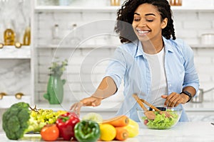 Happy young afro girl preparing vegetable salad