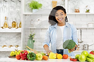 Happy young afro girl preparing vegetable salad for family