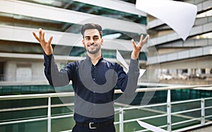 Happy young arab businessman throwing business papers in air outdoors