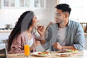 Happy young arab couple enjoying eating their breakfast together at home