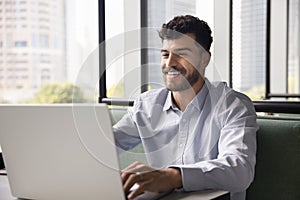 Happy young Arab freelance business man typing on laptop