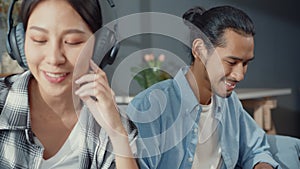 Happy young asia couple activity man use laptop computer work relax enjoy with women wear headphones use smartphone listen music