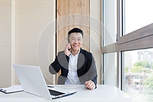 Happy young Asian business man in office looking at mobile phone, with emotion winner or win, financial stock sports betting.