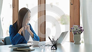 Happy young asian business woman using laptop computer to greeting partner during making video conference with her team