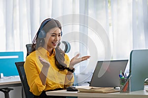 Happy young asian business woman wears headset talk to online video conference call with her business team at modern office or Co-