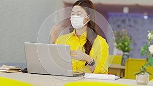 Happy young asian business woman wears surgical face mask meeting online video conference call with her business team at modern