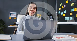 Happy young Asian businesswoman using laptop computer, online video call meeting at home office