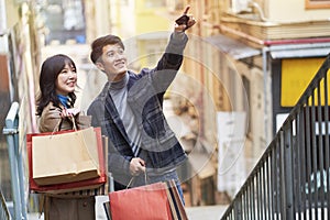 Happy young asian couple shopping in city