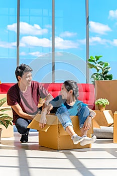 Happy young asian couple smiling relaxing and having fun while playing with cardboard box in new house