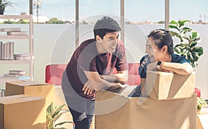 Happy young asian couple smiling relaxing and having fun while playing with cardboard box in new house