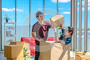 Happy young asian couple smiling relaxing and having fun while playing with cardboard box in new house, celebrating moving to new