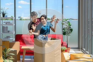 Happy young asian couple smiling relaxing and having fun while playing with cardboard box in new house, moving to new home concept