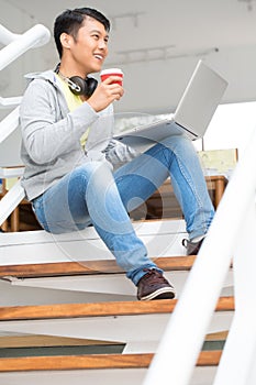 Happy young Asian employee using a laptop in a modern office
