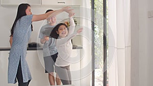 Happy young Asian family listen to music and dancing after breakfast at home. Attractive Japanese mother father and child daughter