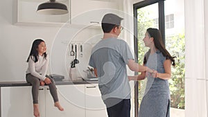 Happy young Asian family listen to music and dancing after breakfast at home. Japanese mother father and child daughter are