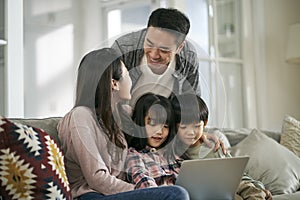 happy young asian family with two children using notebook computer together