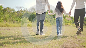 Happy young asian family walking on path holding hands his little girl, They are walk in the park