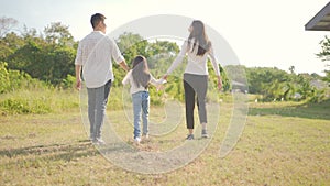 Happy young asian family walking on path holding hands his little girl, They are walk in the park