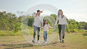 Happy young asian family walking on path holding hands his little girl, They are walk in the park