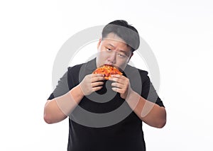 Happy young asian fat man in black polo shirt eating pizza isolated over white background.
