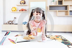 happy young asian girl eat milk cookie biscuit with dairy fresh milk for breakfast in morning after finish homework from school