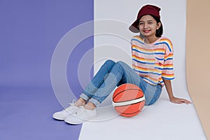 Happy young asian girl palying basketball with pastel background