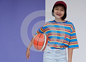 Happy young asian girl palying basketball with pastel background