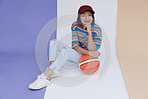 Happy young asian girl palying basketball with pastel background