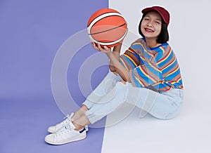 Happy young asian girl palying basketball with pastel background