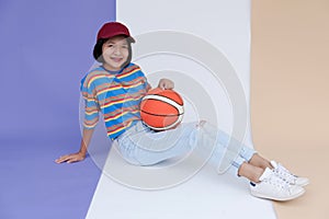 Happy young asian girl palying basketball with pastel background