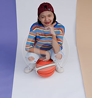 Happy young asian girl palying basketball with pastel background