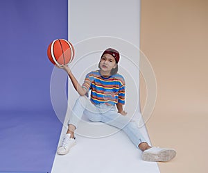 Happy young asian girl palying basketball with pastel background