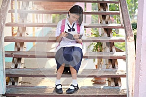 Happy young asian girl reading book at school