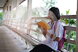 Happy young asian girl reading book at school