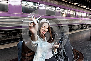 Happy young Asian lady tourist with model airplane at train station. Travel lifestyle concept