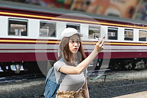 Happy young Asian lady tourist with model airplane at train station. Travel lifestyle concept